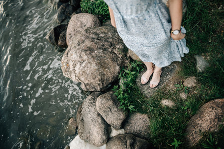 A girl stands on the seashore near large stones. View from aboveの写真素材