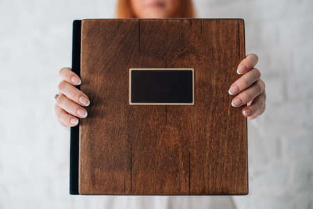 the girl holds on her outstretched arms a blank of a wooden book with a place for writing text or a...