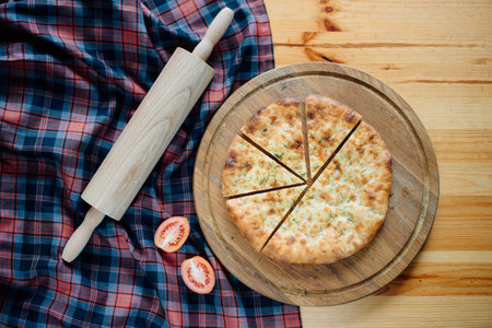 homemade pizza on wooden board, rolling pin and tomatoes