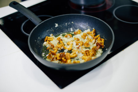 a frying pan on the stove in which mushrooms and onions are friedの写真素材