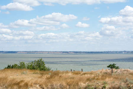 large bay with bright turquoise water, grass burnt by the sun on the shoreの写真素材
