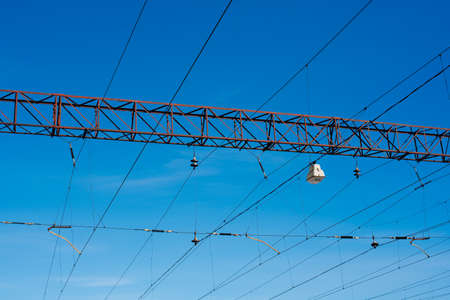 Overhead railway power lines and holding structures under blue sky