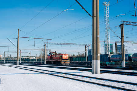 Overhead railway power lines and holding structures under blue sky and train