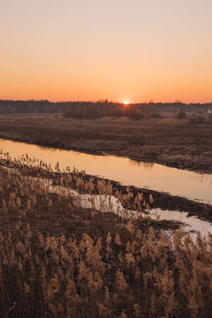 Sunset over narrow river in spring