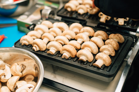 Champignons are fried on an electric grillの写真素材