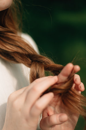 Red-haired girl braids her hair. High quality photo