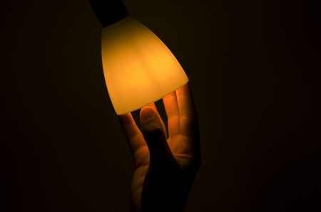 A hand reaching inside a lamp