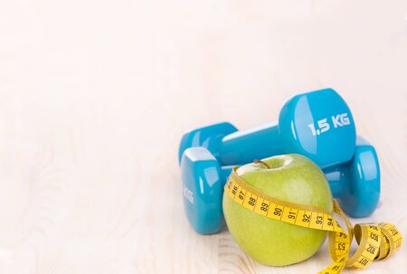 Dumbbells and apple on white, wooden backgroungの写真素材
