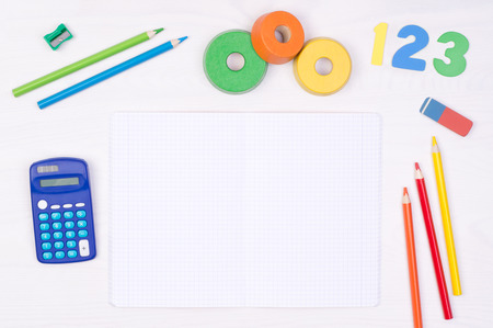 Learning maths. Kid's desk with blank notebook, colorful pencils, numbers and a calculator, top view...