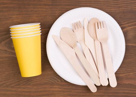 Disposable paper plates and cups and wooden cutlery on wooden tableの写真素材