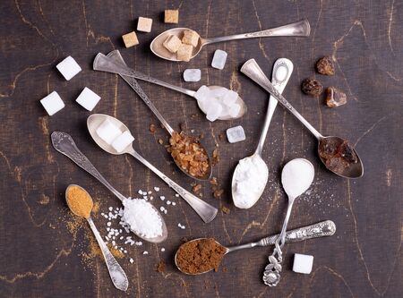 Various kinds of sugar in old spoons on dark wooden backgroundの写真素材