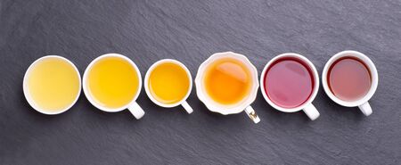 Assortment of tea cups on dark, stone background, top viewの写真素材