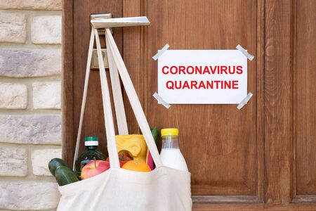 Grocery shopping in a bag hanging on door handle during a quarantineの写真素材