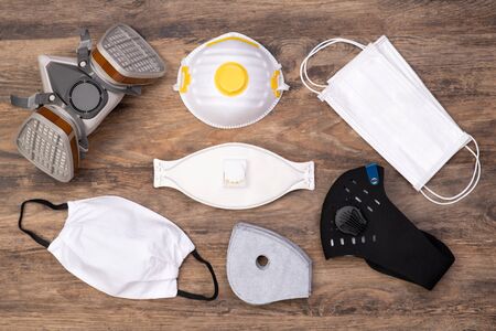 Different types of protective masks on wooden background, top view
