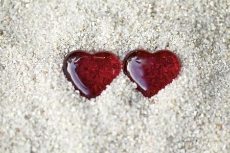 Two red hearts with stones on the sandの写真素材