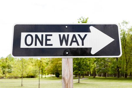 One way road sign, green grass and tree in the background.の写真素材
