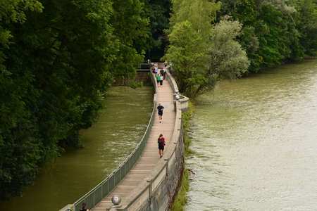 people walking on pedestrian bridge over river in summerの写真素材