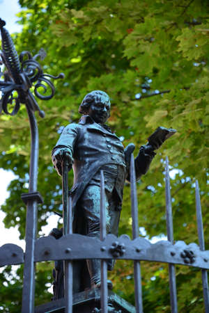 Bronze statue of a man standing in front of an iron gateの写真素材
