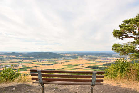 Wooden bench on top of a hill with a view of the valley and mountainsの写真素材