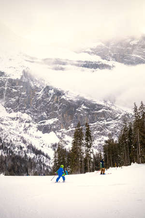Boy skiing with his father on a cloudy day in Switzerlandの写真素材