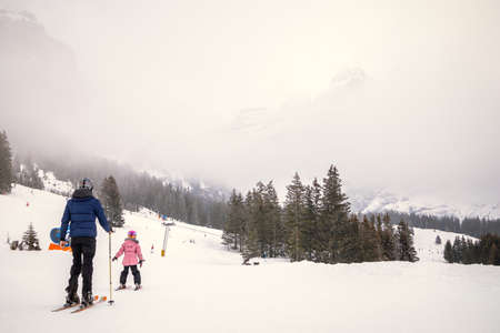 Father and daughter skiing on cloudy day in the mountainsの写真素材