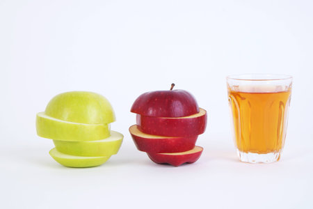 Apple sliced sections and apple juice. Red and green apple on wood table. Apple juiceの写真素材