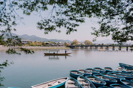 KYOTO, JAPAN - APRIL 3, 2023 : Tourists enjoy sakura trees from boat at Arashiyama river.のeditorial素材