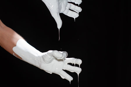 The hands of a man in white paint on a black backgroundの写真素材
