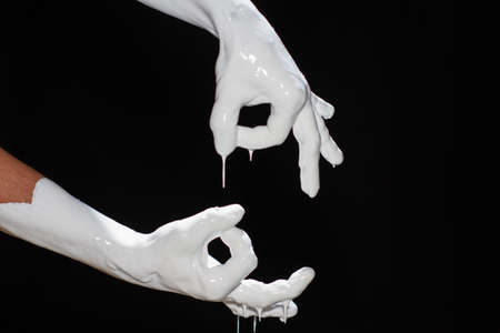 The hands of a man in white paint on a black backgroundの写真素材