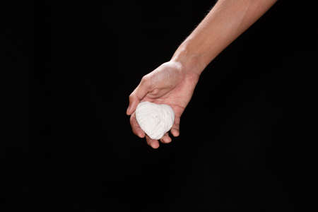 The hands of a man in white paint on a black background. Heart in hand on a dark background.の写真素材