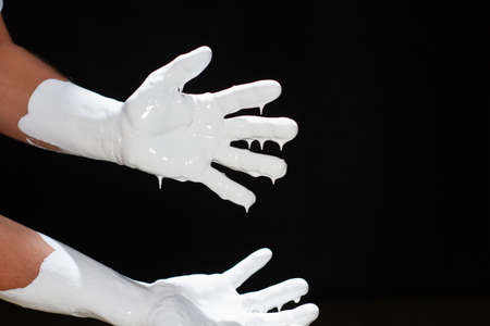 The hands of a man in white paint on a black backgroundの写真素材