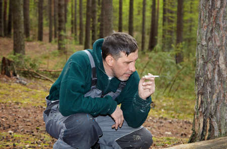 A man smokes in the forest. Smoke break in the forest.