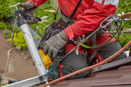 Sealing of the metal roof with rope access. The installer seals the roof.