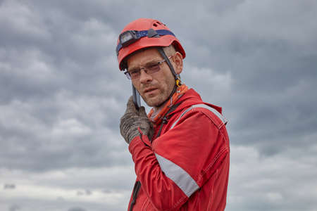 Roof repair. Installation of a metal roof. A man in a red suit works on a red roof. Work at a...