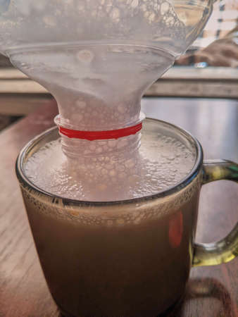 Milk is poured into a dark glass from a plastic bottleの写真素材