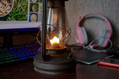 A kerosene lamp stands on a computer table. computer and oil lampの写真素材