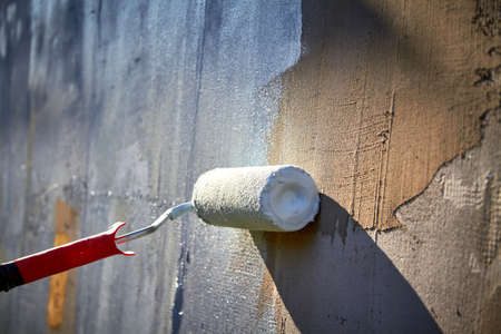 I paint the house with a roller with blue paint.の写真素材