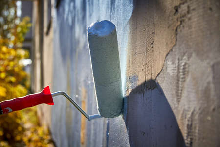 I paint the house with a roller with blue paint.の写真素材