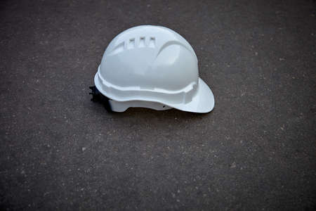 The construction helmet is white. Construction helmet on asphalt. White helmet for safety on the construction siteの写真素材