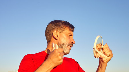 A man shave. Shaving outside at dawn. Shave in the rays of the rising summer sun.