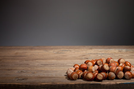Nuts lie on an old wooden table on a dark background.の写真素材