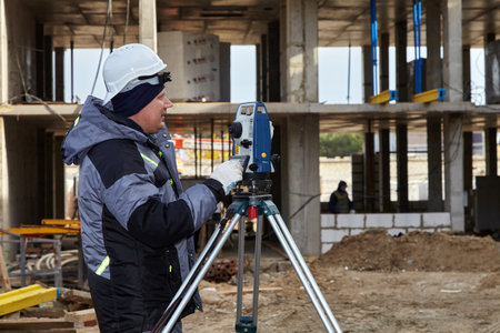Work with theodolite. An engineer works with a theodolite on a construction site.のeditorial素材