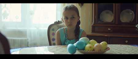 Portrait of little girl with Easter eggs on the table at homeの素材