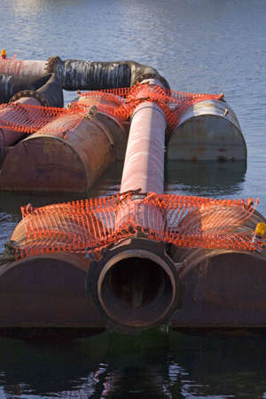 Harbor dredging pipes being held by barrels waiting to be used.の写真素材