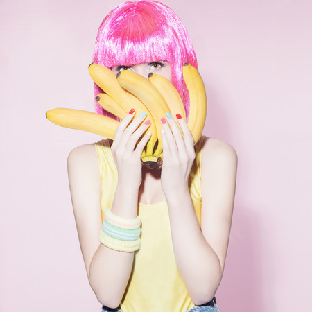 beauty young woman with pink bob hairstyle.Beautiful girl with bananas.healthy food conceptの写真素材