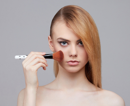 beautiful girl with make-up brush.beauty woman Applying Make-up.clean skin cosmetics.Young woman face with perfect skinの写真素材