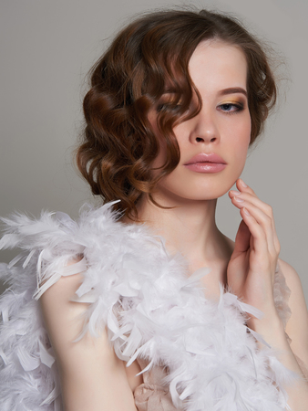 beautiful young woman in feather boa. Healthy hair beauty girl with make-up and curly hairの写真素材