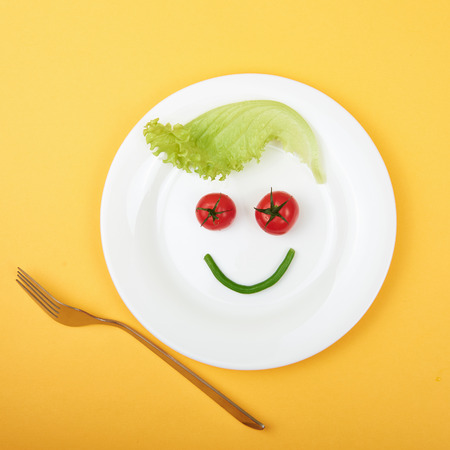 healthy food still life. vegetarian plate.funny face from vegetablesの写真素材