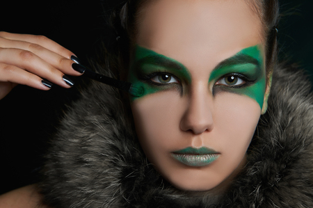 fantasy woman in fur doing makeup.fairy make-up beautiful girl painted her faceの写真素材