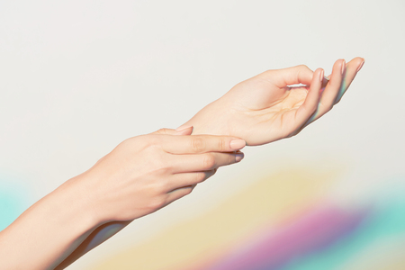 hands of a young woman with manicure on nails against the light colored spotlights backgroundの写真素材